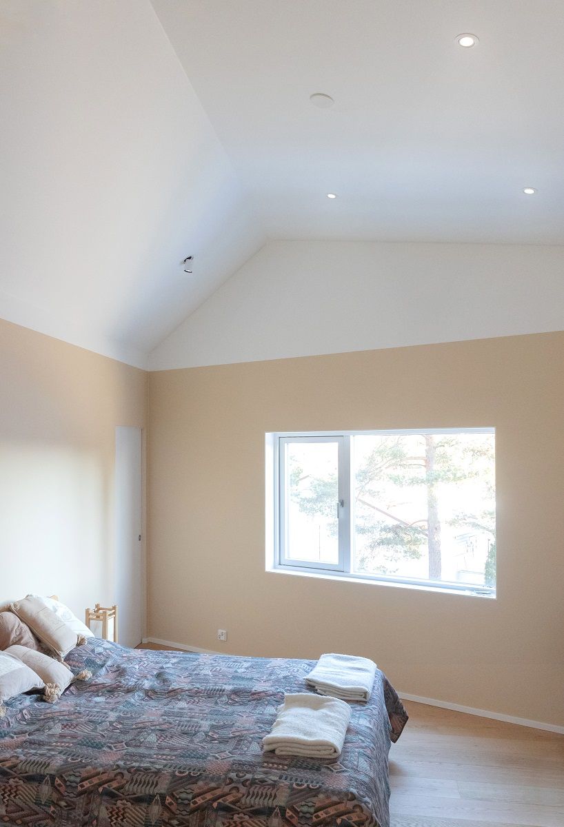 Una camera da letto alta illuminata da faretti direzionali a incasso e da faretti KOLO.